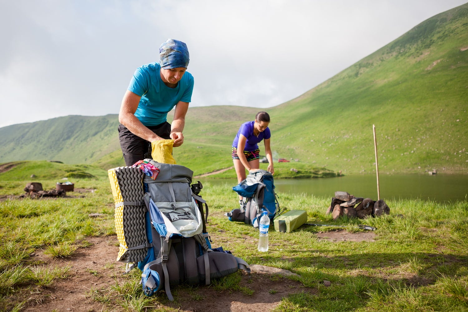 Two female backpackers re-packing their packs on the trail.