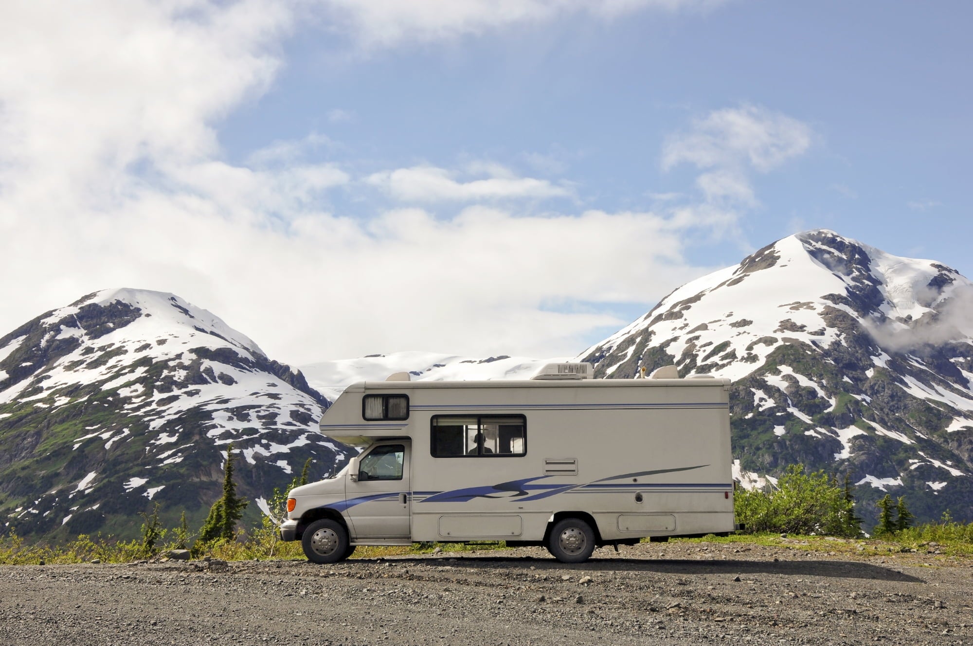 parked rv with snowcapped mountains just beyond it