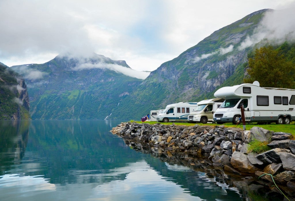 line of rvs next to water and in front of mountains