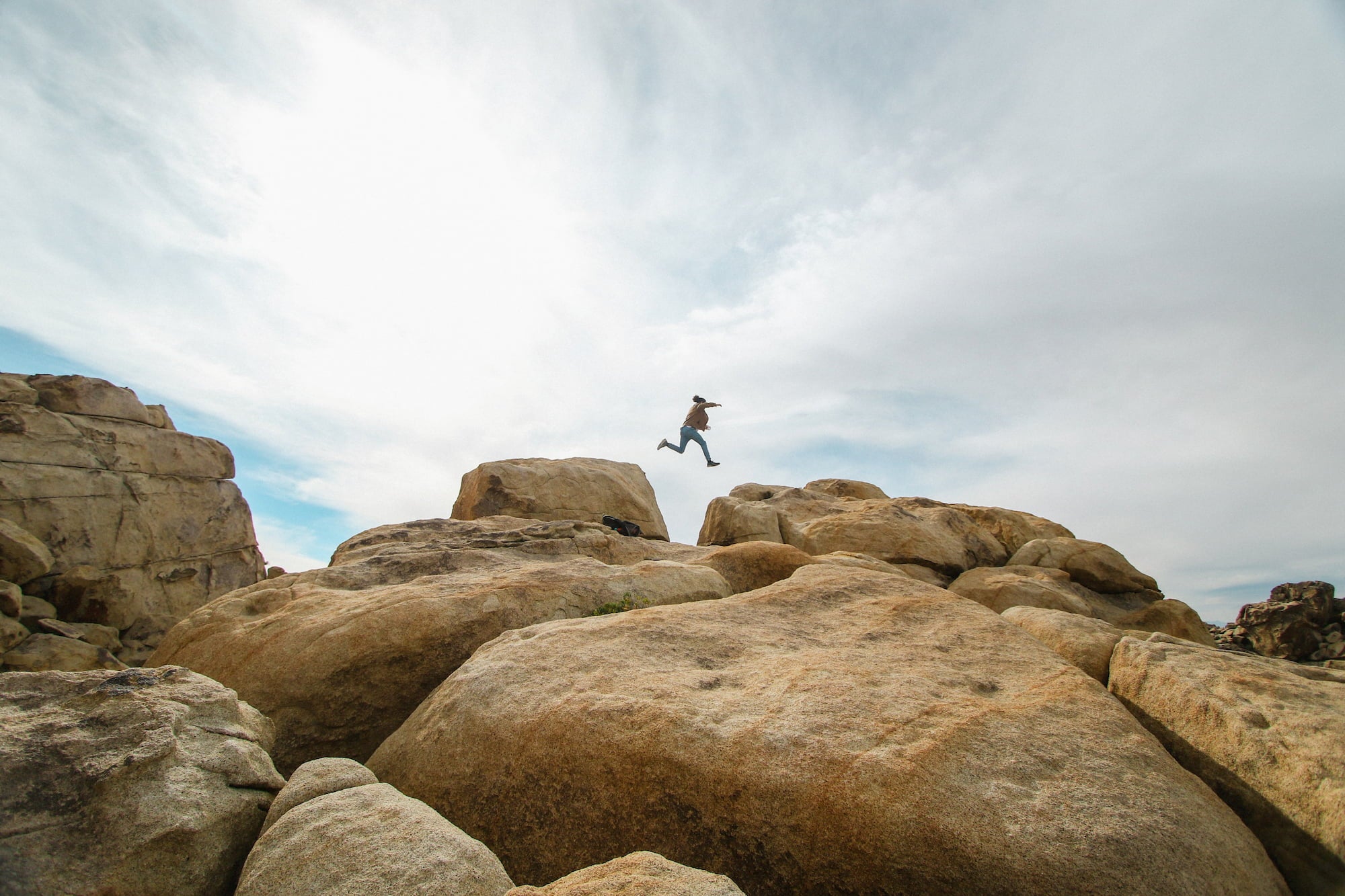 Person running and jumping over large boulders.