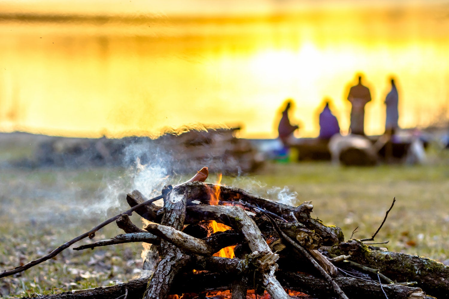 group of friends in background with unattended fire in the foreground