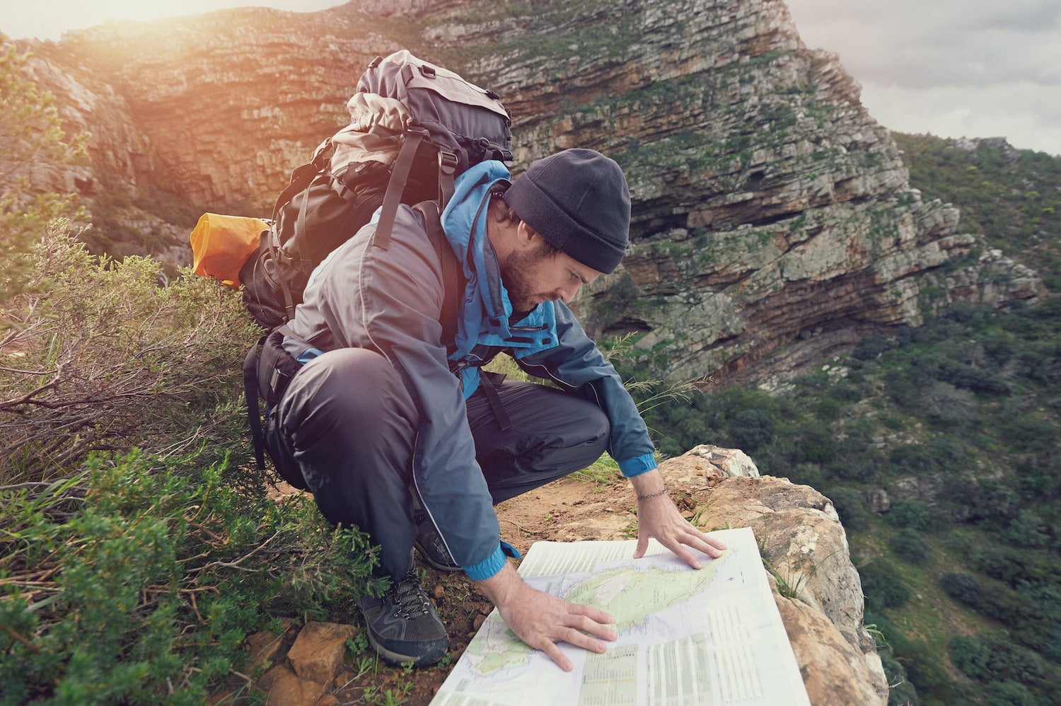 backpacking man looking at a map spread out over a rock