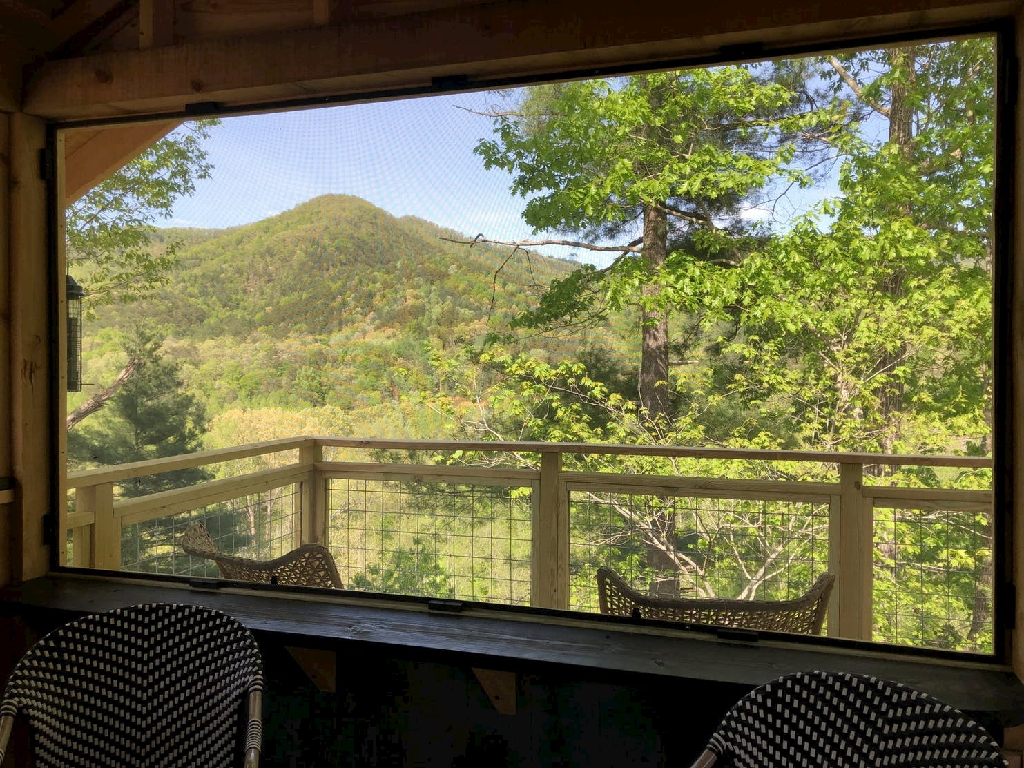 Image of green forested mountains through the window of a cabin.