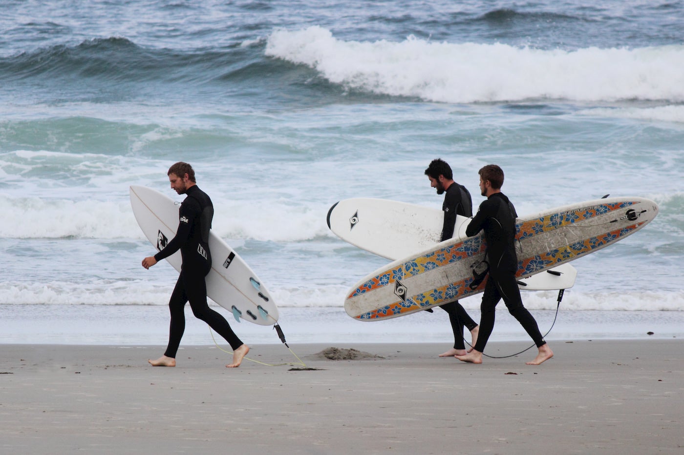 Surfers carrying their boards along the coast in Biddeford Maine.