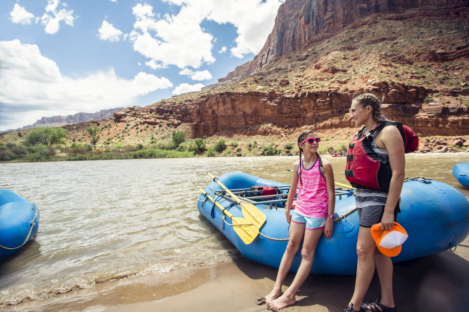 woman and child stand next to raft on bank of the colorado river