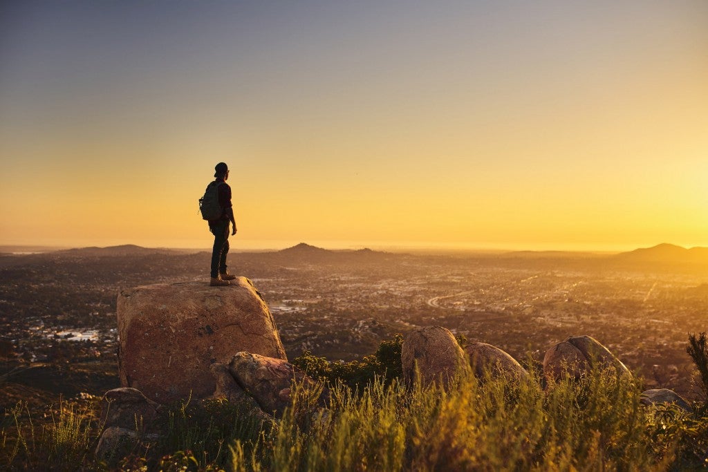 man on rock with landscape at sunset