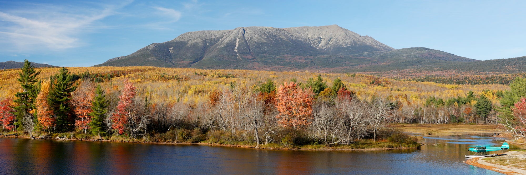 Fail foliage surrounding a flat top mountain under sunny blue skies.