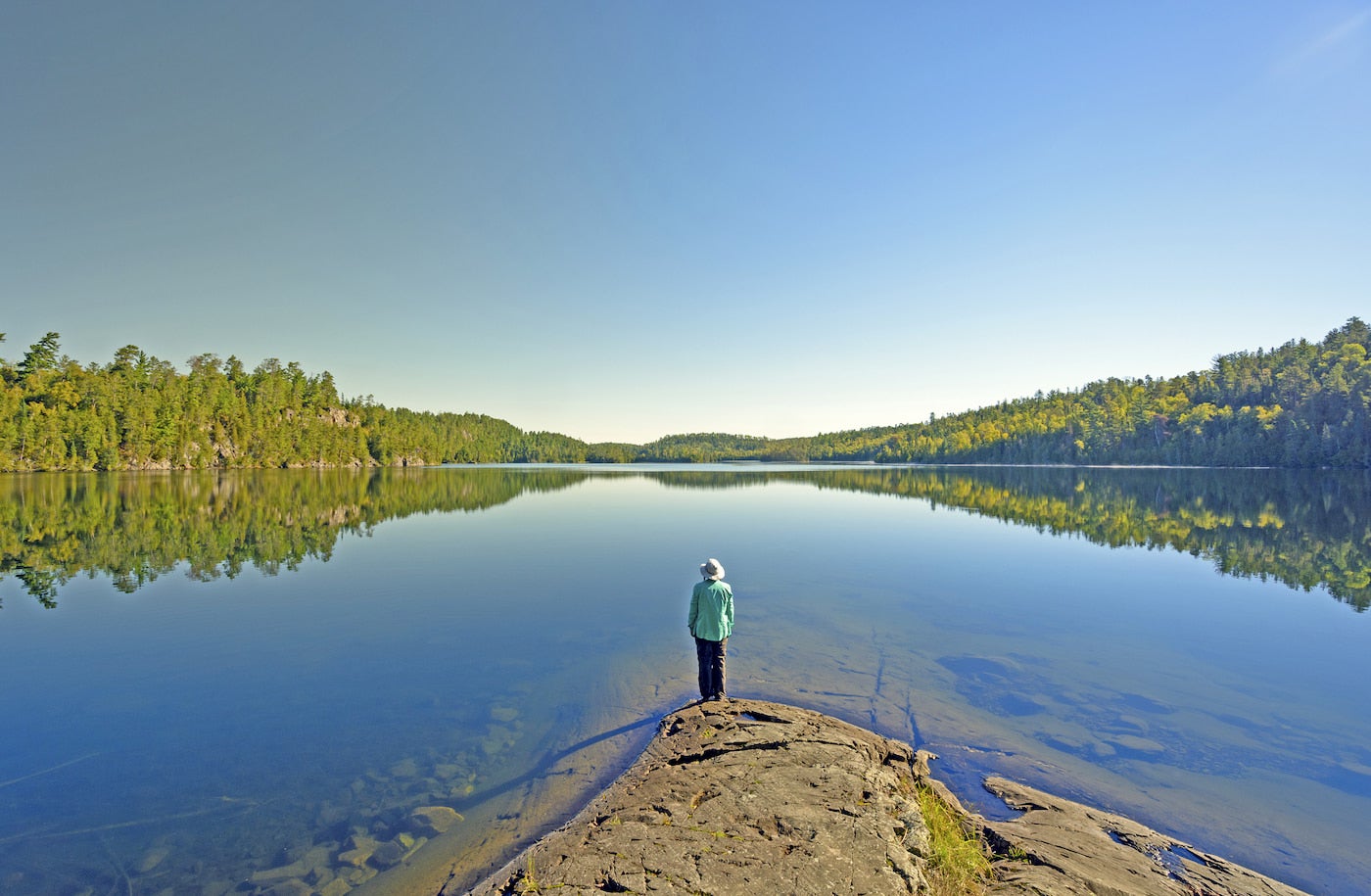 Person standing on the edge of the water at a lake.