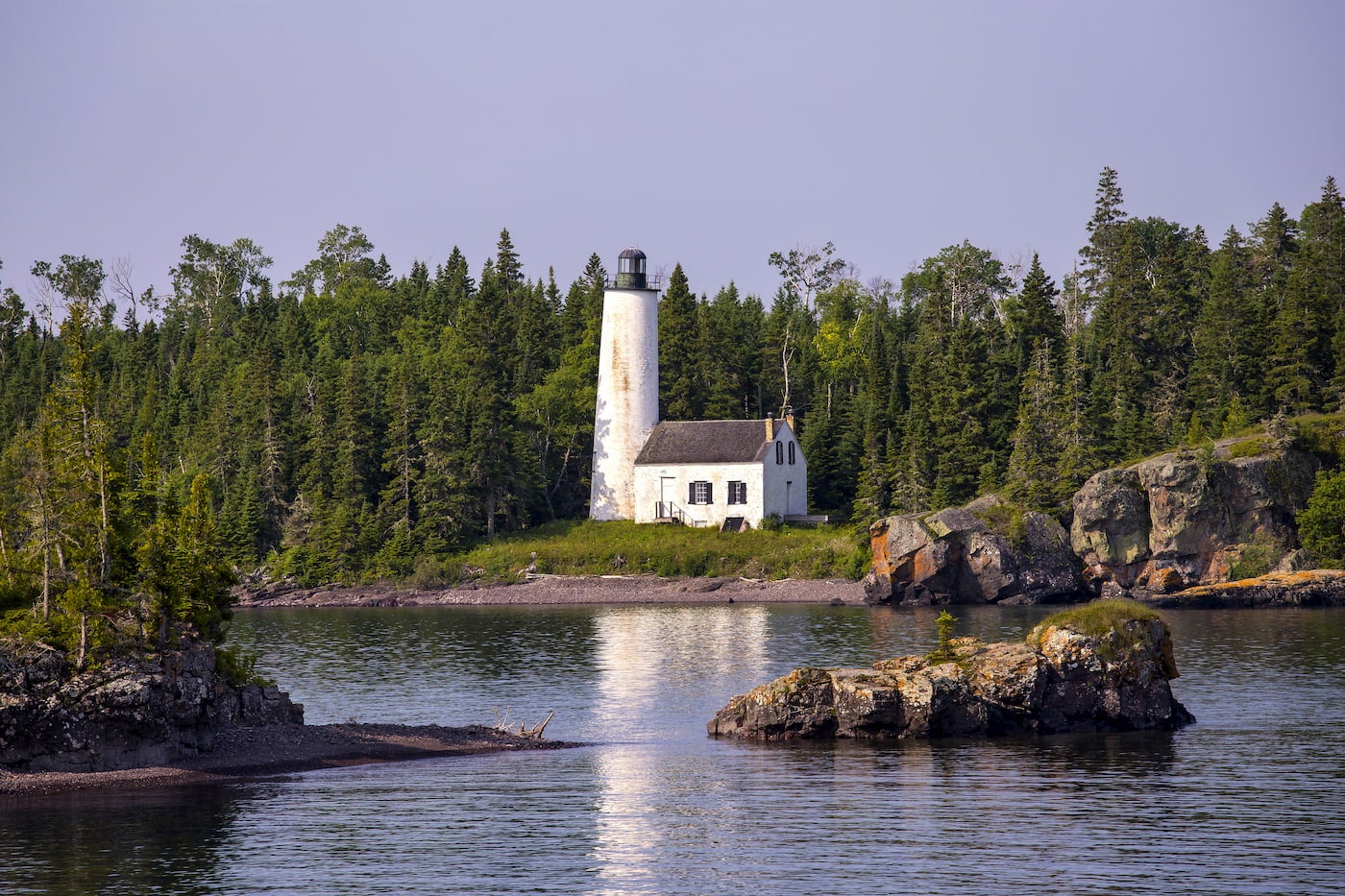 White lighthouse on the coast of a forested island.