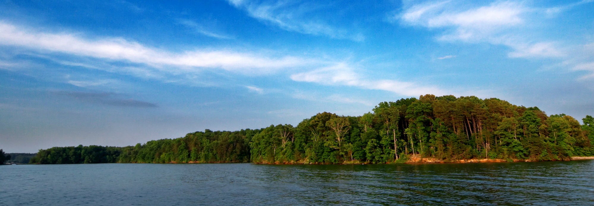 wispy clouds and trees above smith mountain lake
