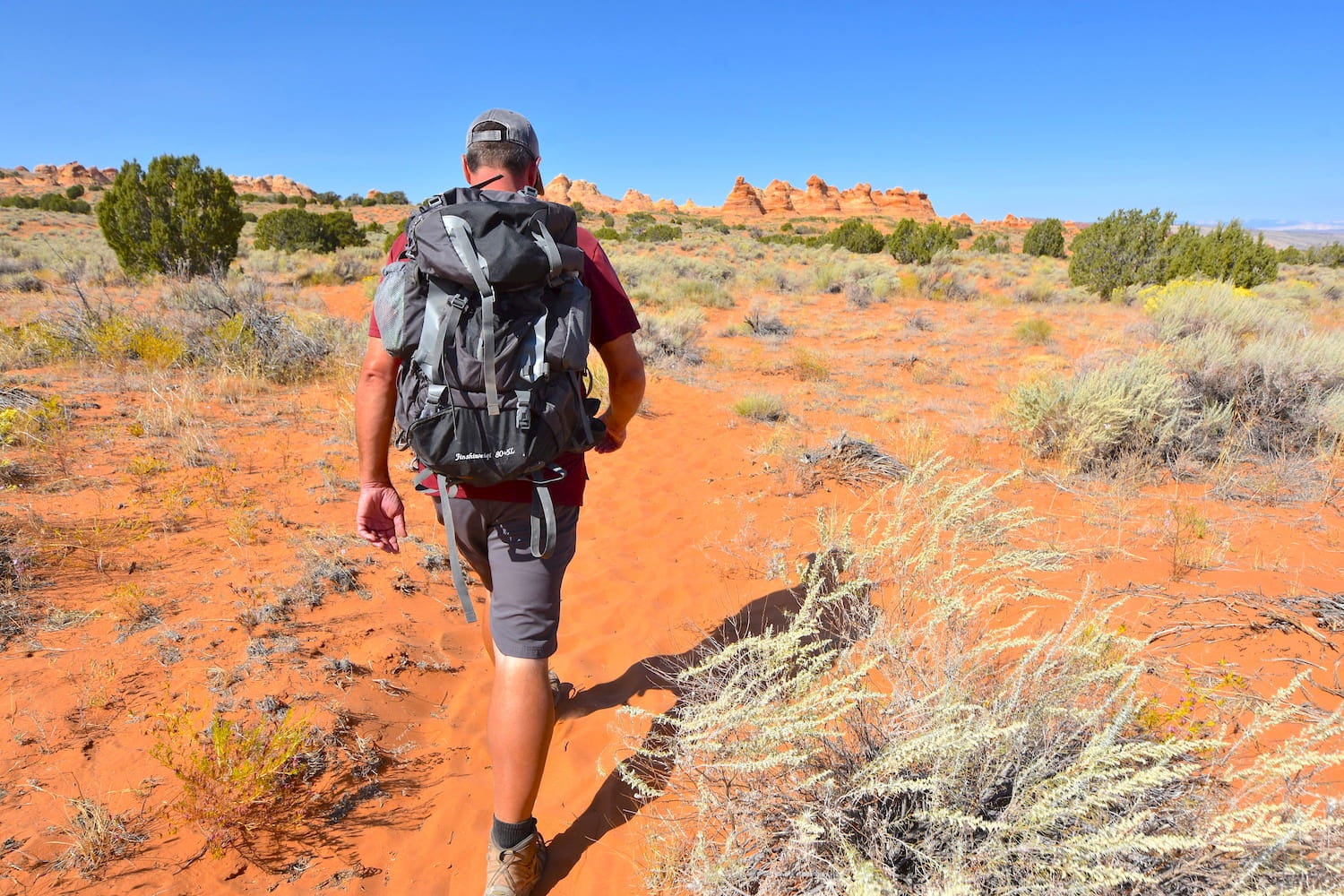 Bakcpacker hiking through red rock desert.