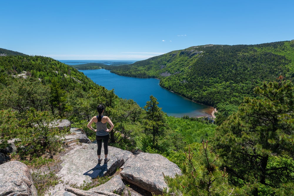 a hiker on the egde of a cliff in acadia national park