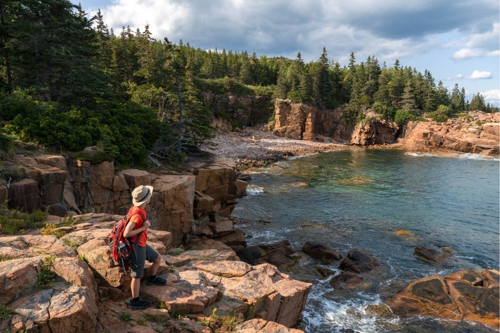 a hiker on the coast of maine hiking in acadia national park