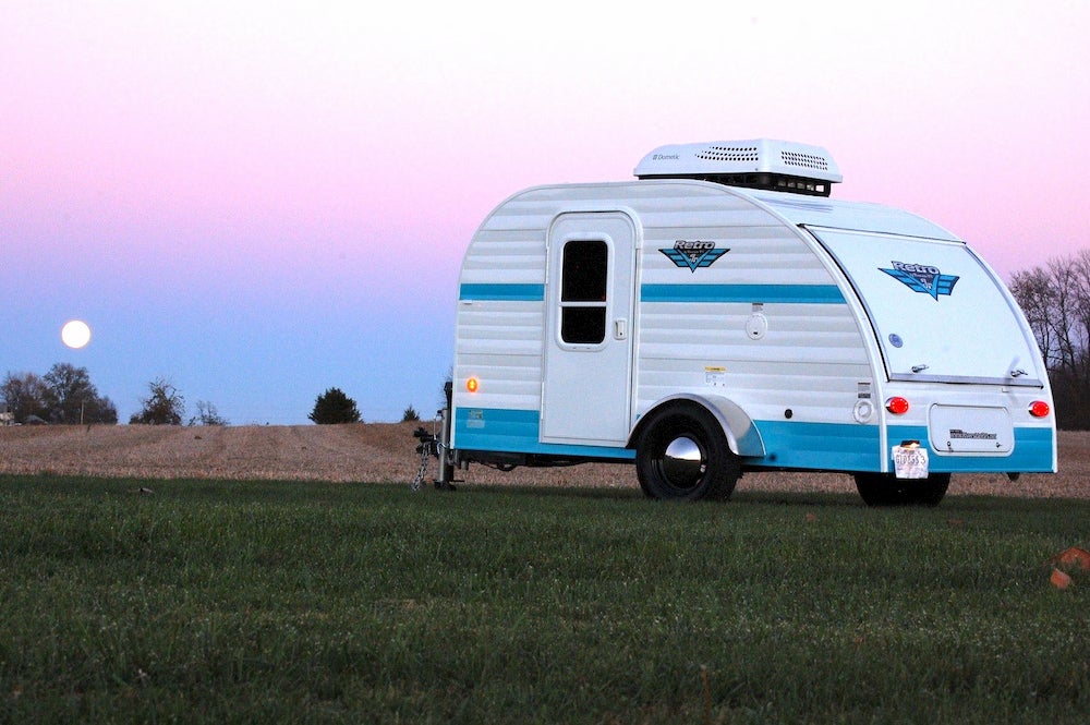 Blue and white vintage camper with sunset in background