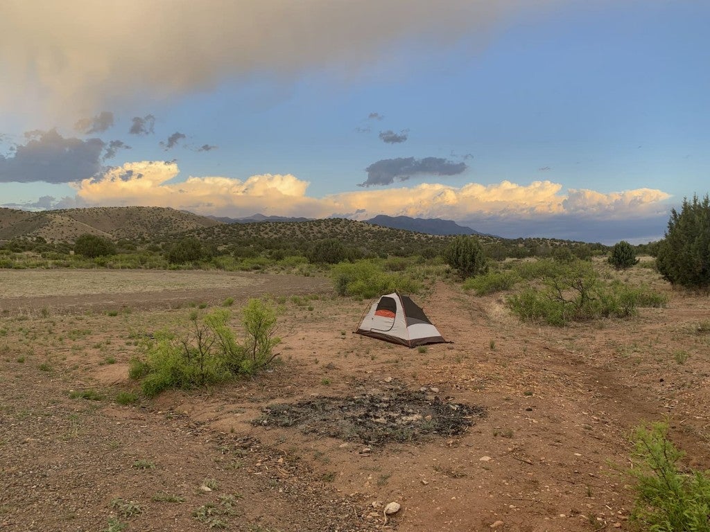 Small tent setup in expansive mountain desert landscape.