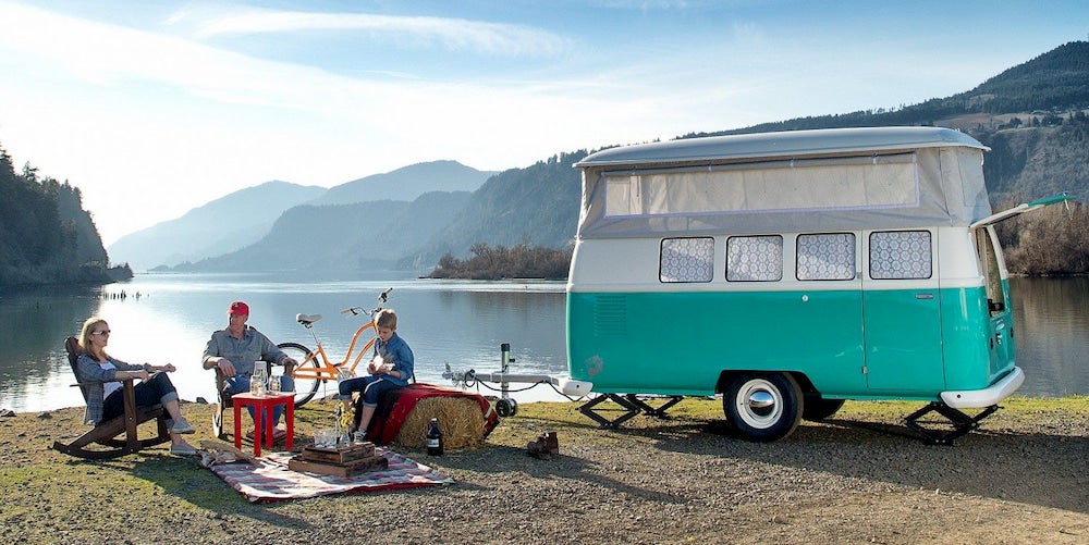 Família ao lado do lago com campista vintage turquesa