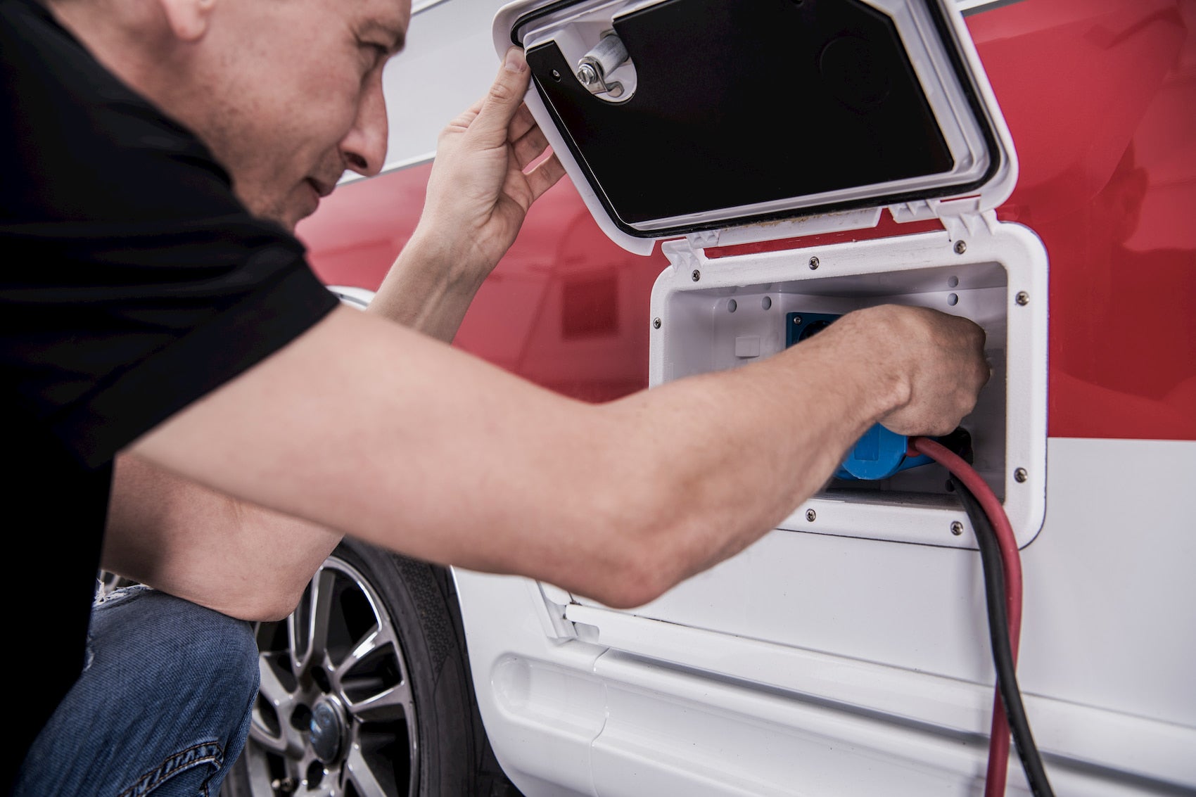 Man setting up electrical plug on RV exterior.