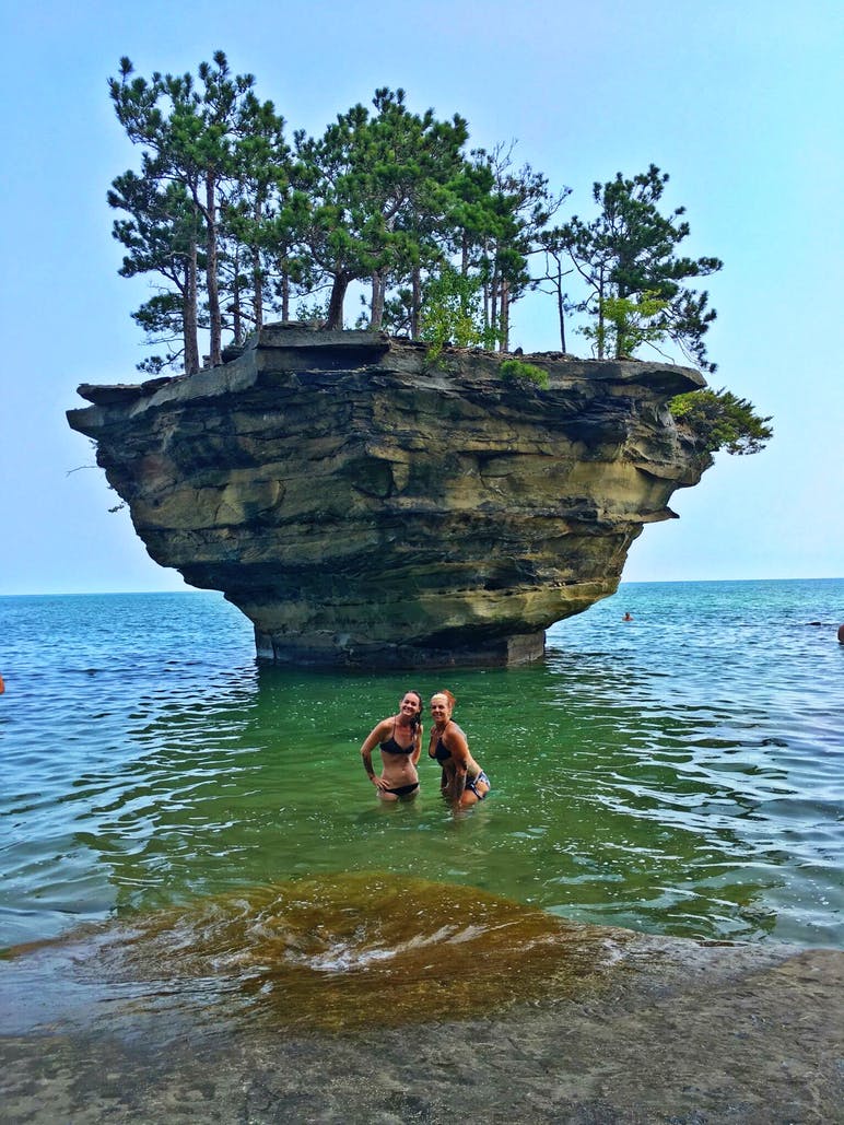 women posing in front of rock formation in lake