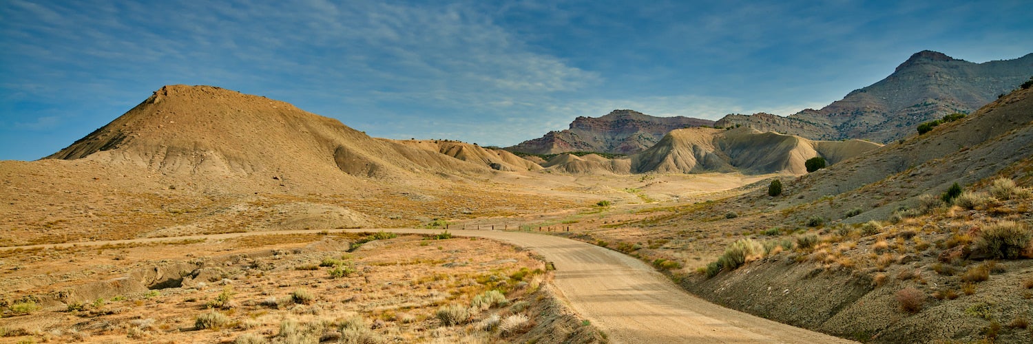 dirt road winding into vast desert valley