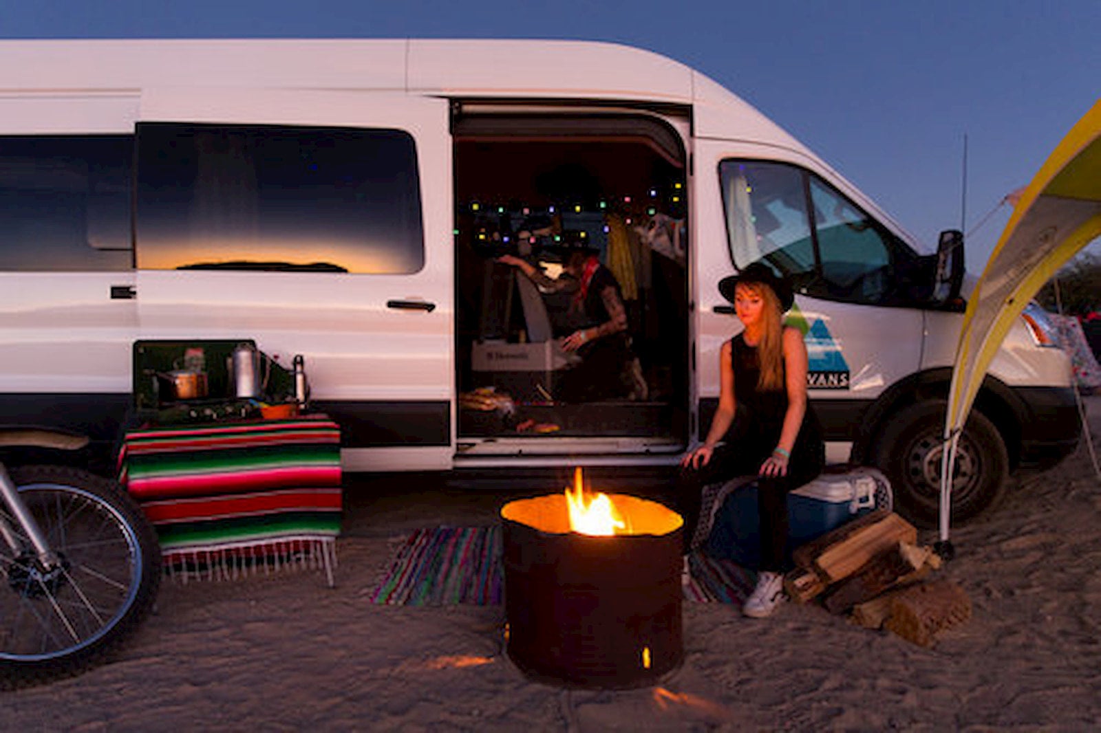 Women sitting in fron of fire pit and sprinter van rental.