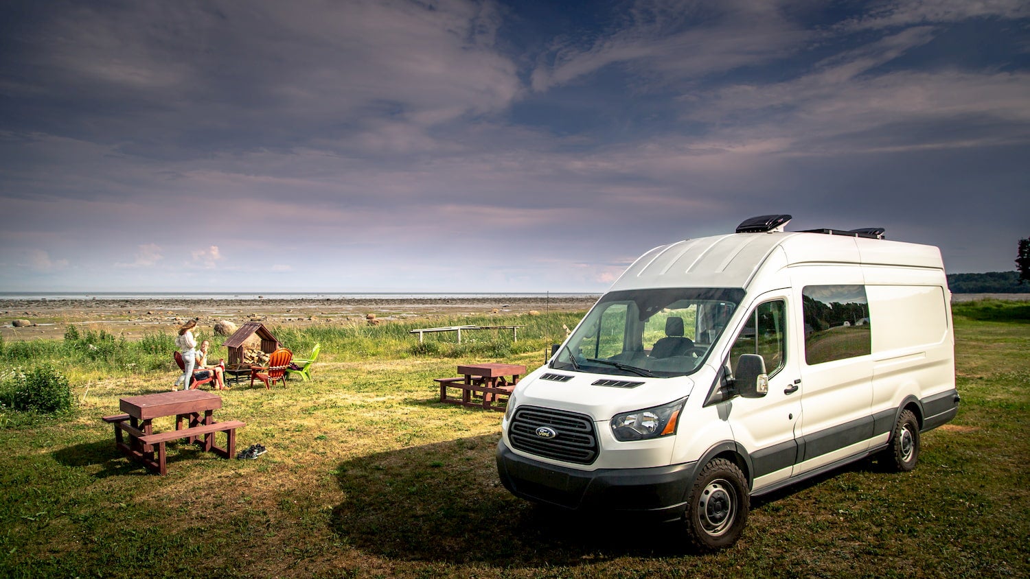 Camper van parked next to picnic table.