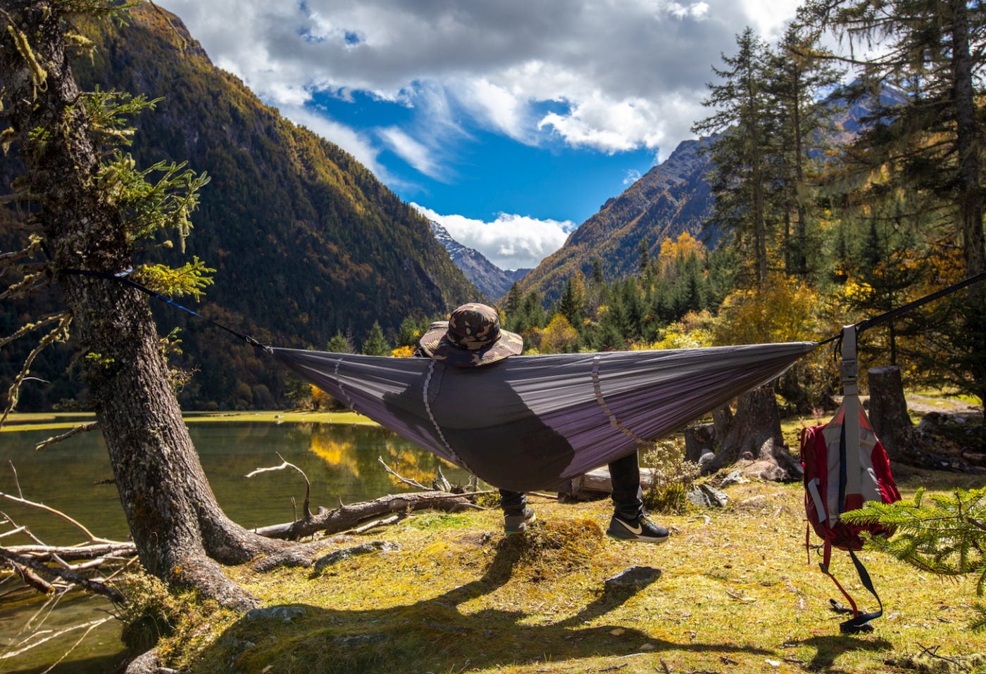 Person lounging in camping hammock with built in bug net in the mountains.