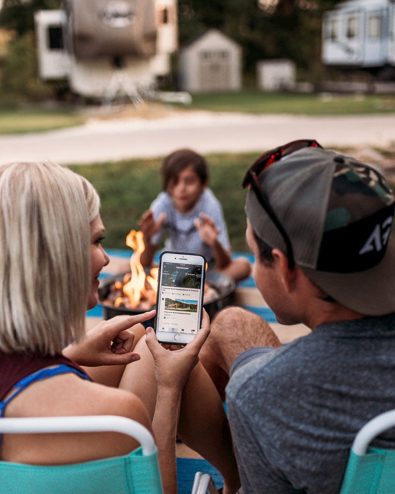 Family sitting around campfire looking at The Dyrt camping app.