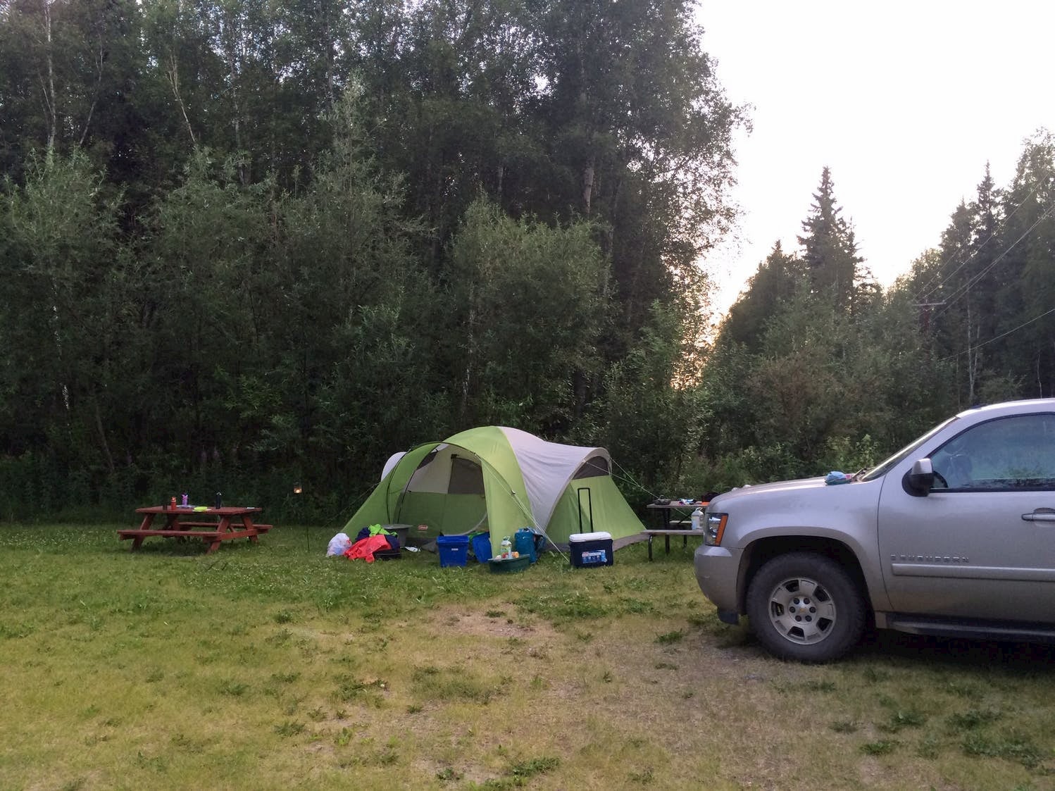 Campsite with pitched tent and fire pit beside the forest.