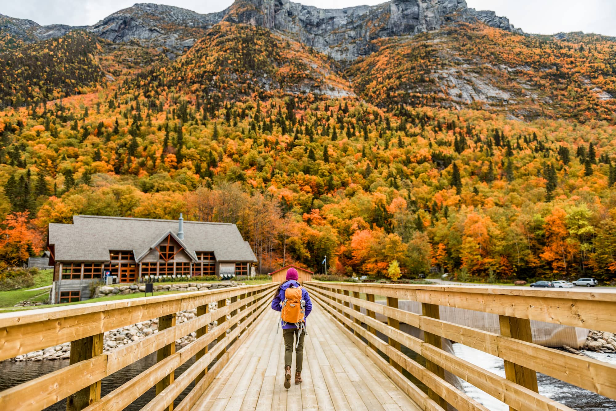 Women hiking through mountain landscape as trees change color in the Fall.