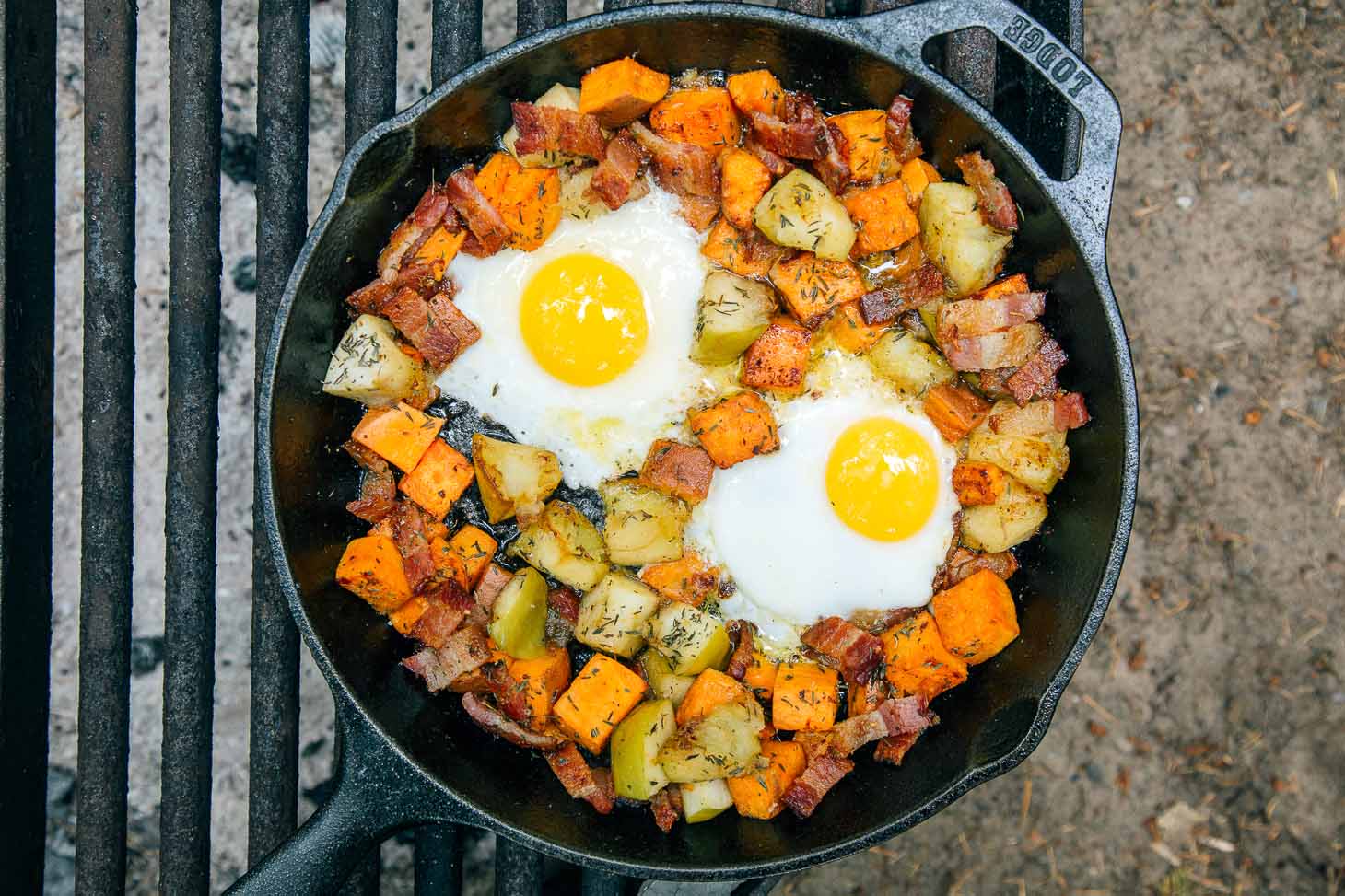 Cast iron skillet of sweet potato hash with eggs.