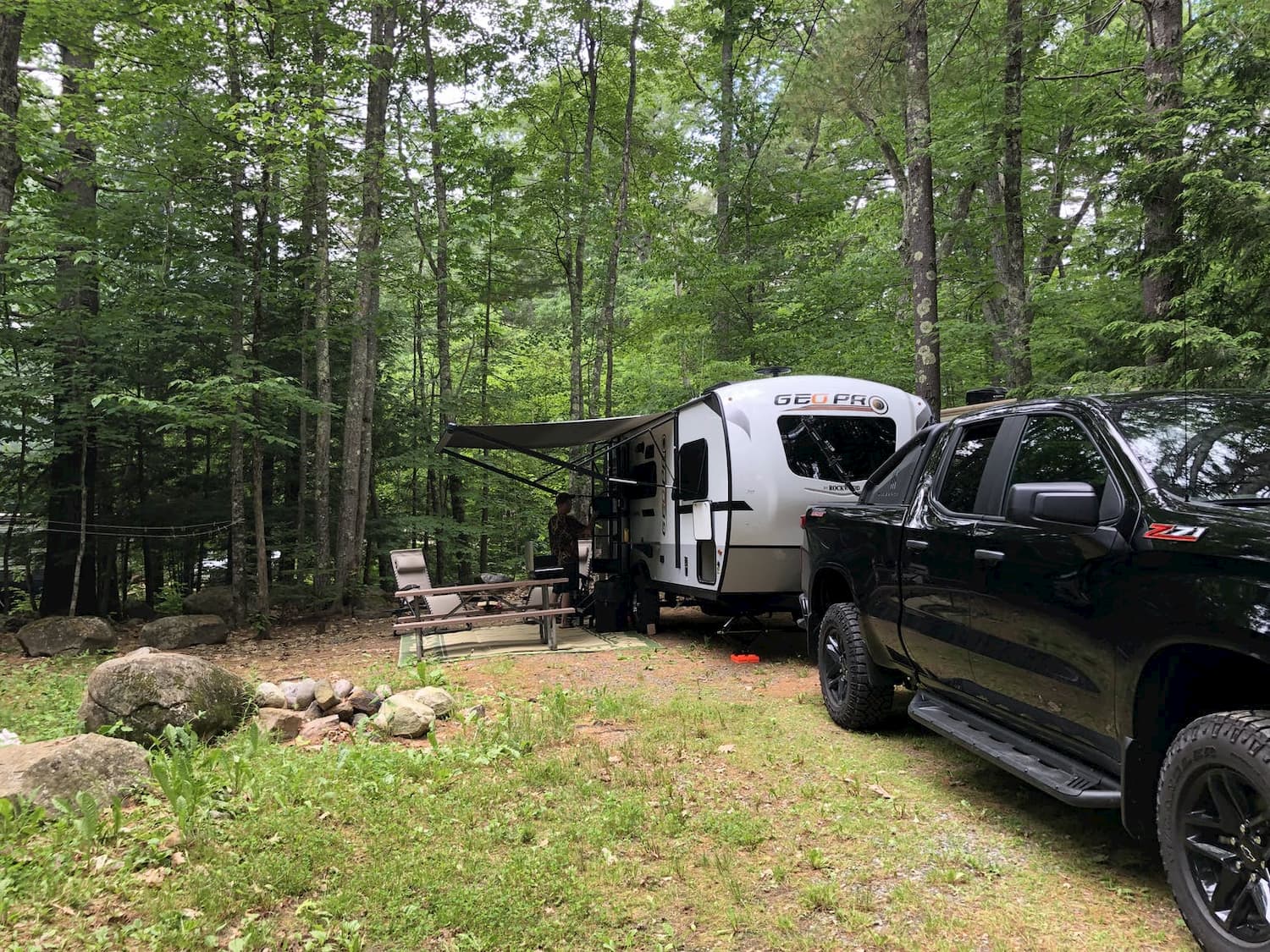 truck with pull-behind parked at forested campsite