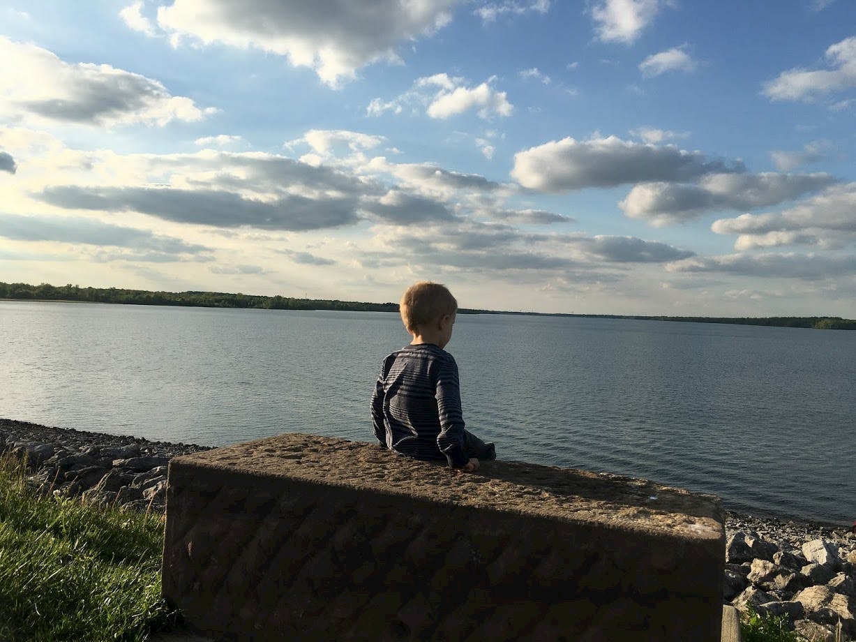 small child sitting overlooking lake