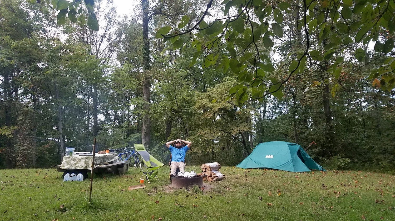 man sitting at campsite with tent set-up