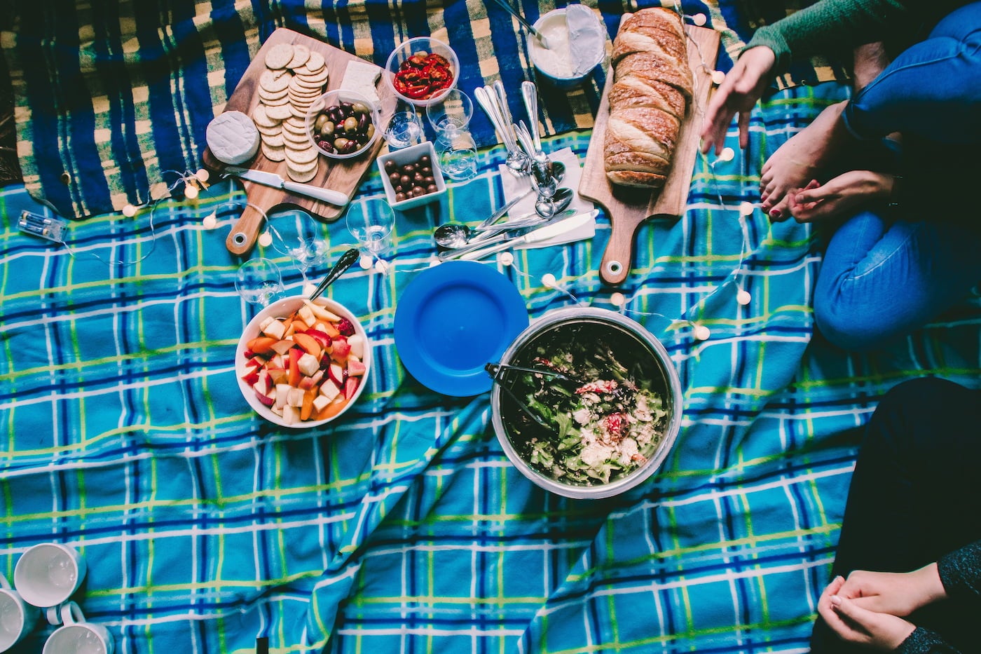 Charcuterie picnic on blankets outdoors.