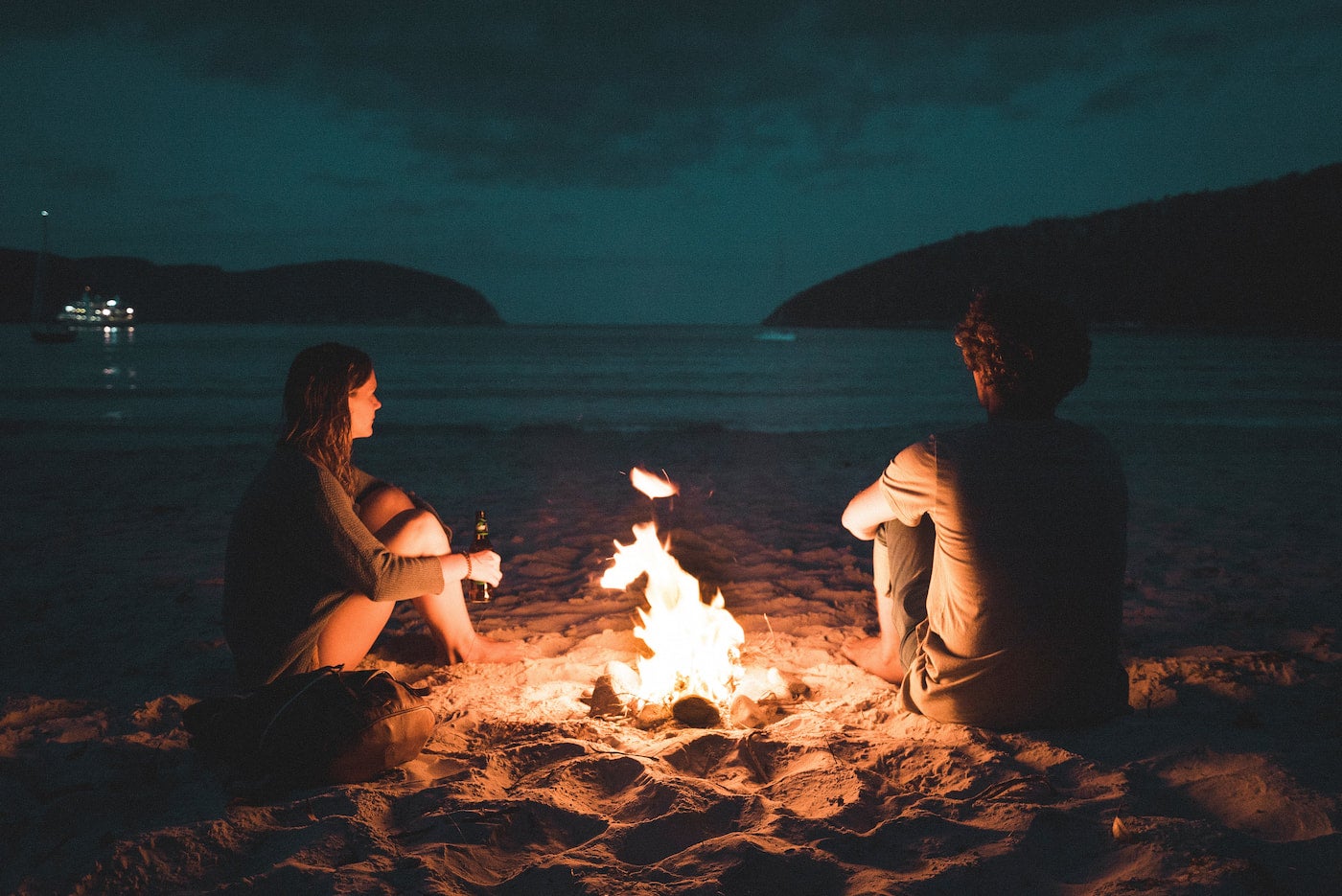 A couple hanging out around a campfire.