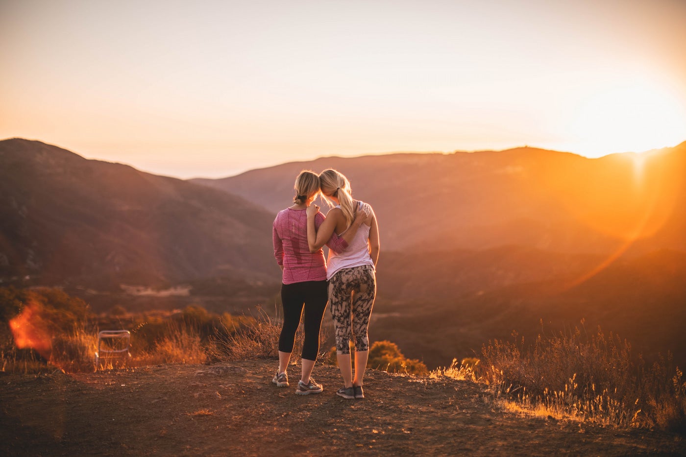 Women hugging while watching the sunset.