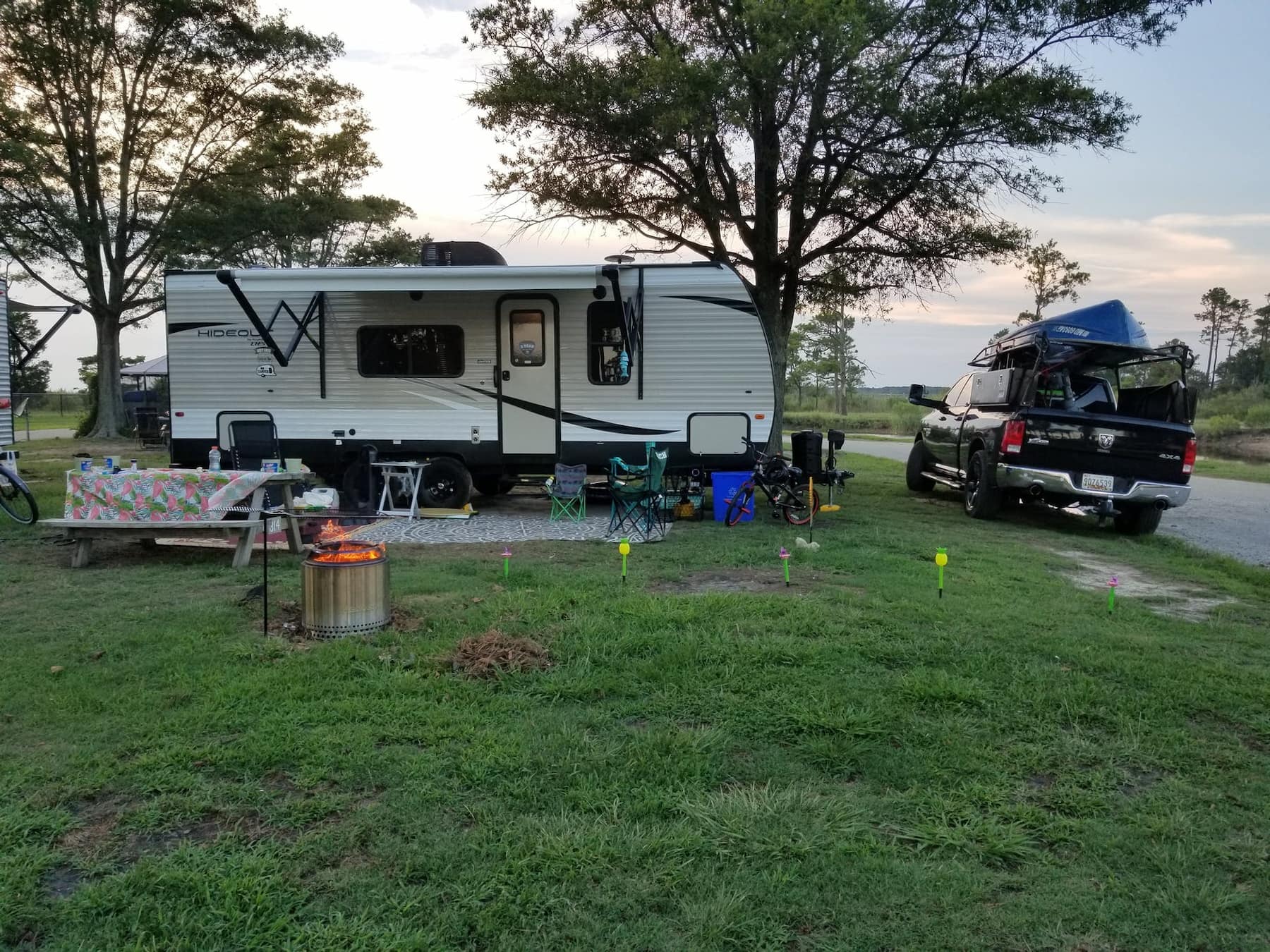 RV parked beside the Virginia coast at a campsite beside a fire pit and picnic table.