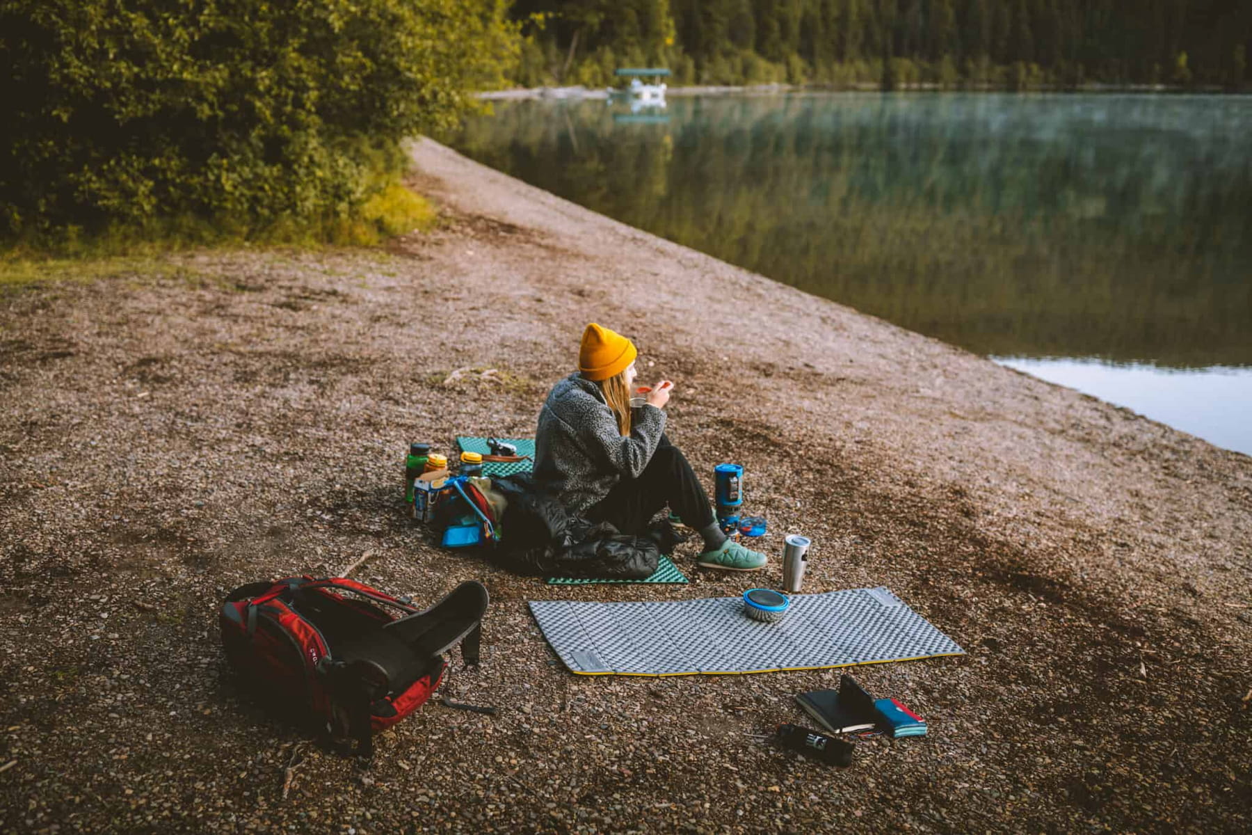 Women sitting on Z-pad on the shore of a lake.