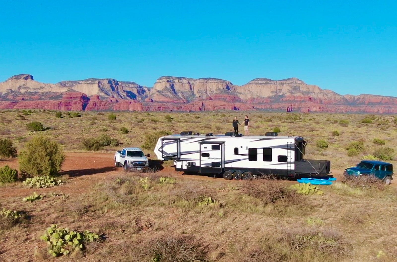 Tom and Cheri standing on top of their RV in the desert.