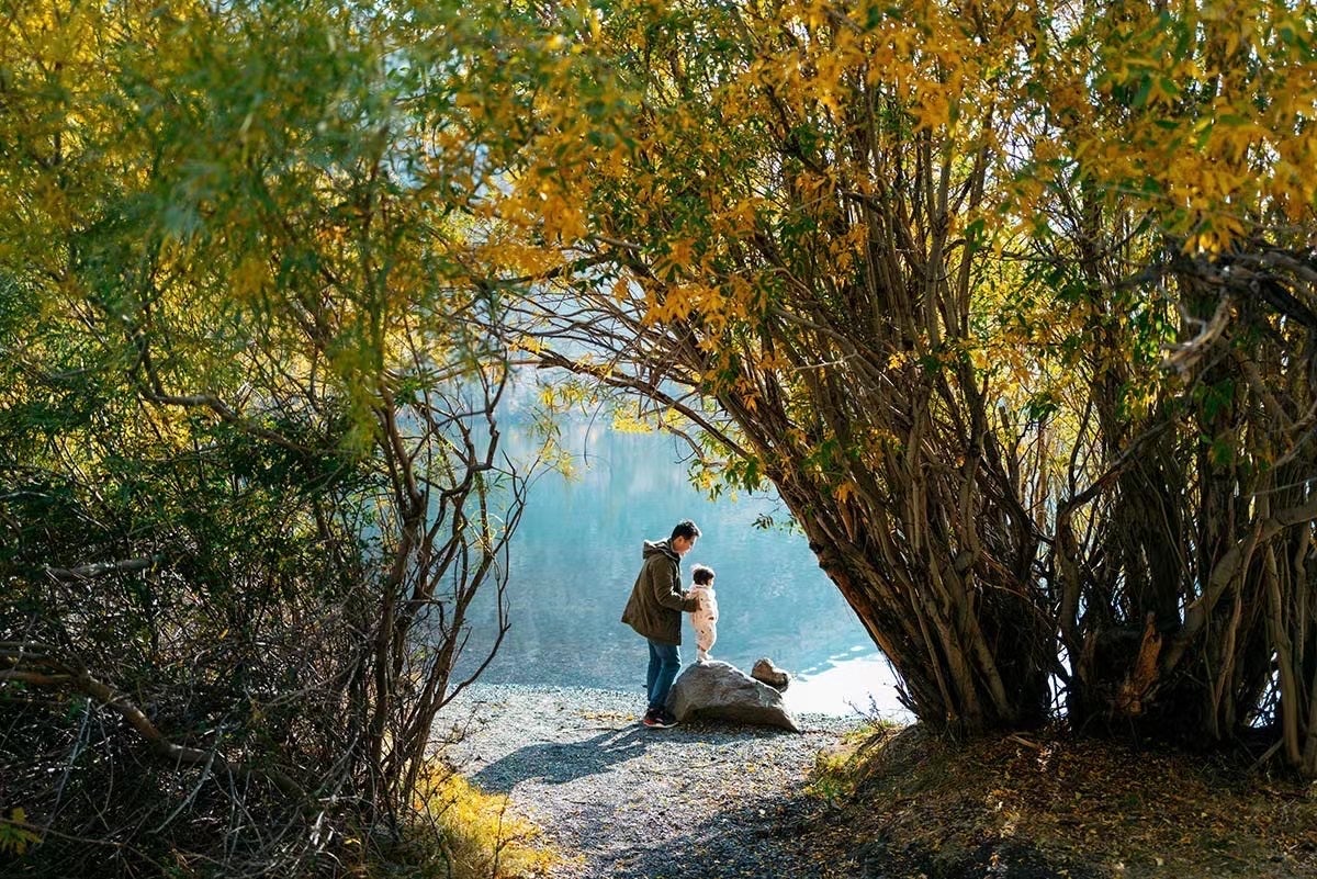 man and daughter standing by lake