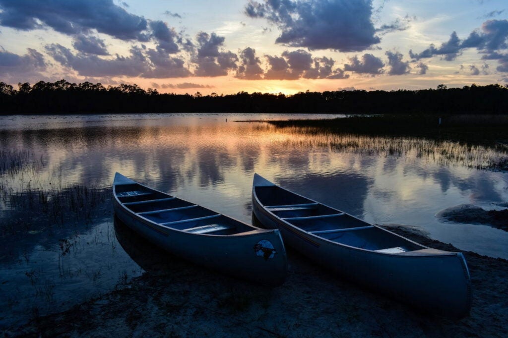 Canoes on the shore during sunset at campsite in Florida.