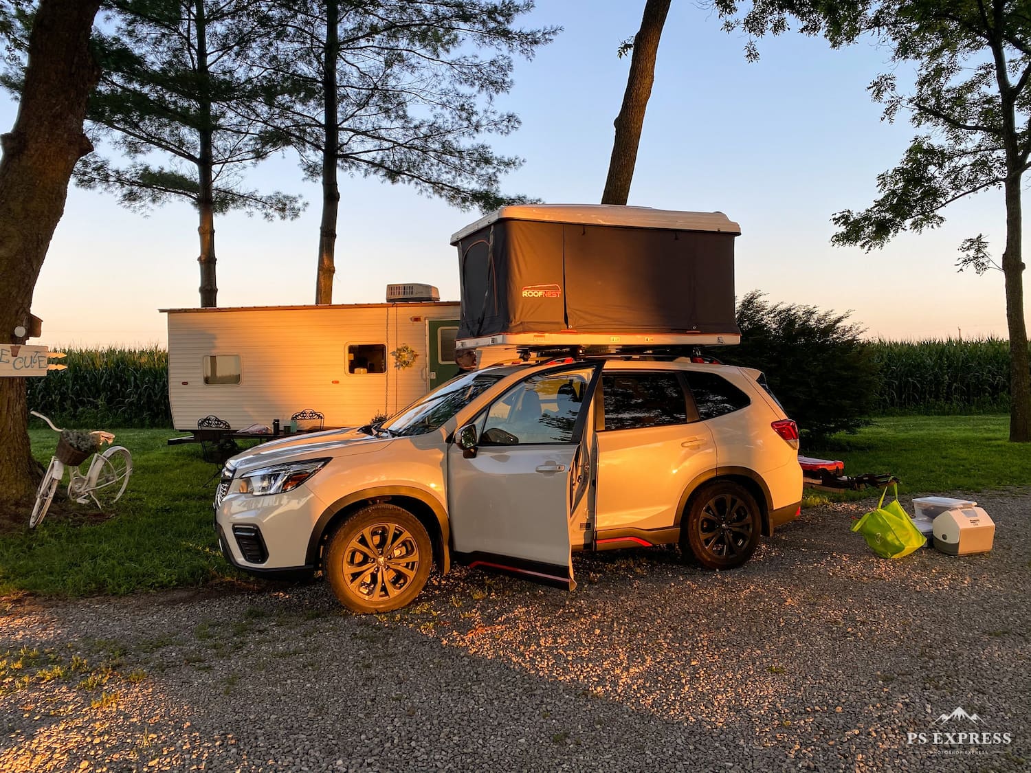 Golden hour at a wooded campsite with a car with a rooftop tent.
