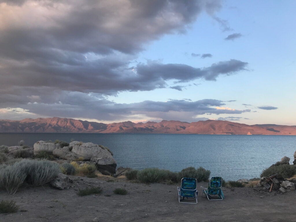 Sunset over pyramid lake campsite with beach chairs overooking the mountain landscape.