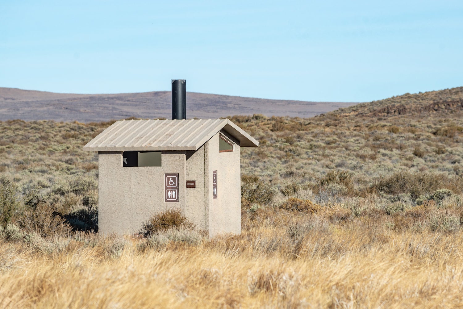 vault toilet in grassy field