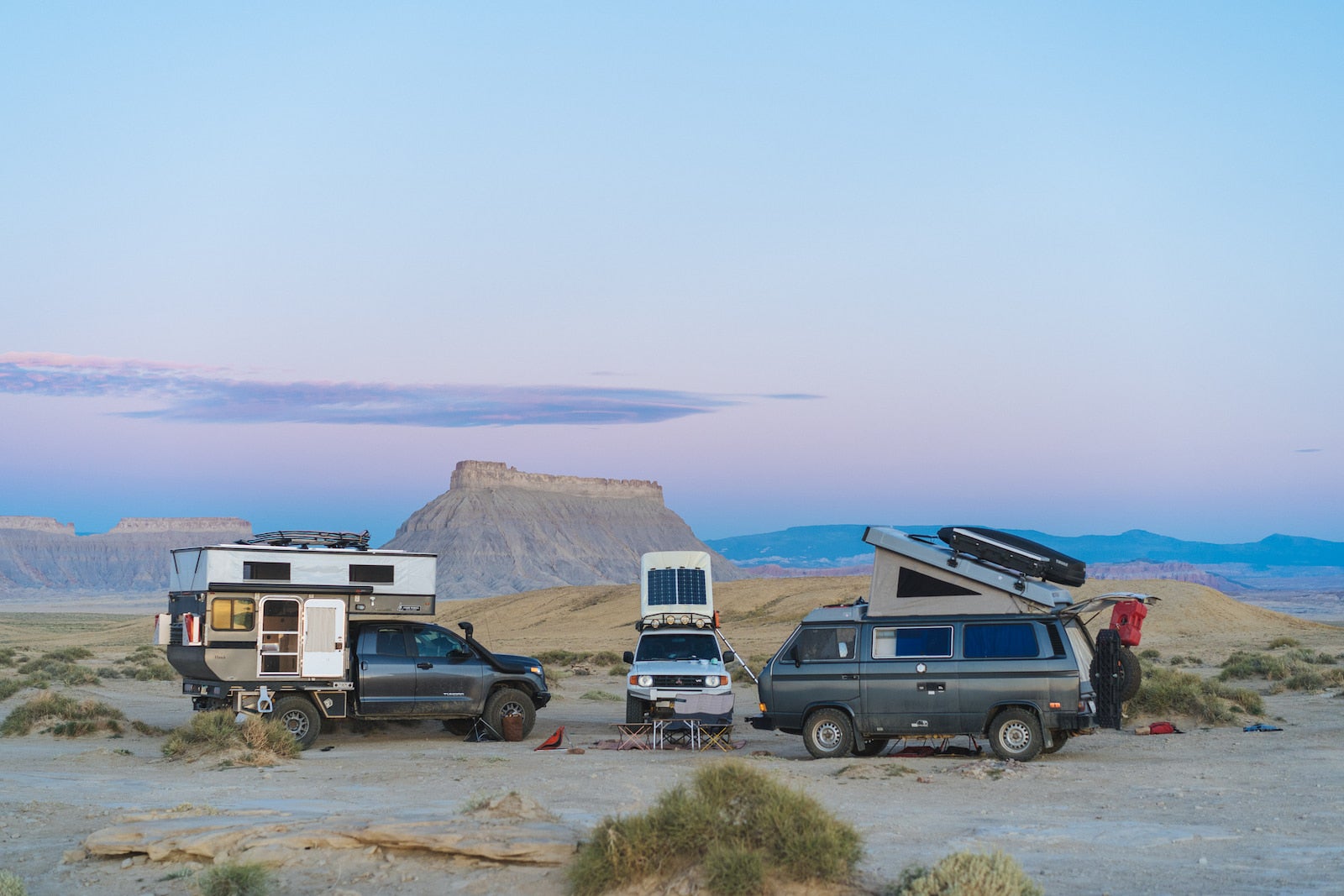 Bound for nowhre's rig parked next to two VW vans surrounded by the desert and rock formations.