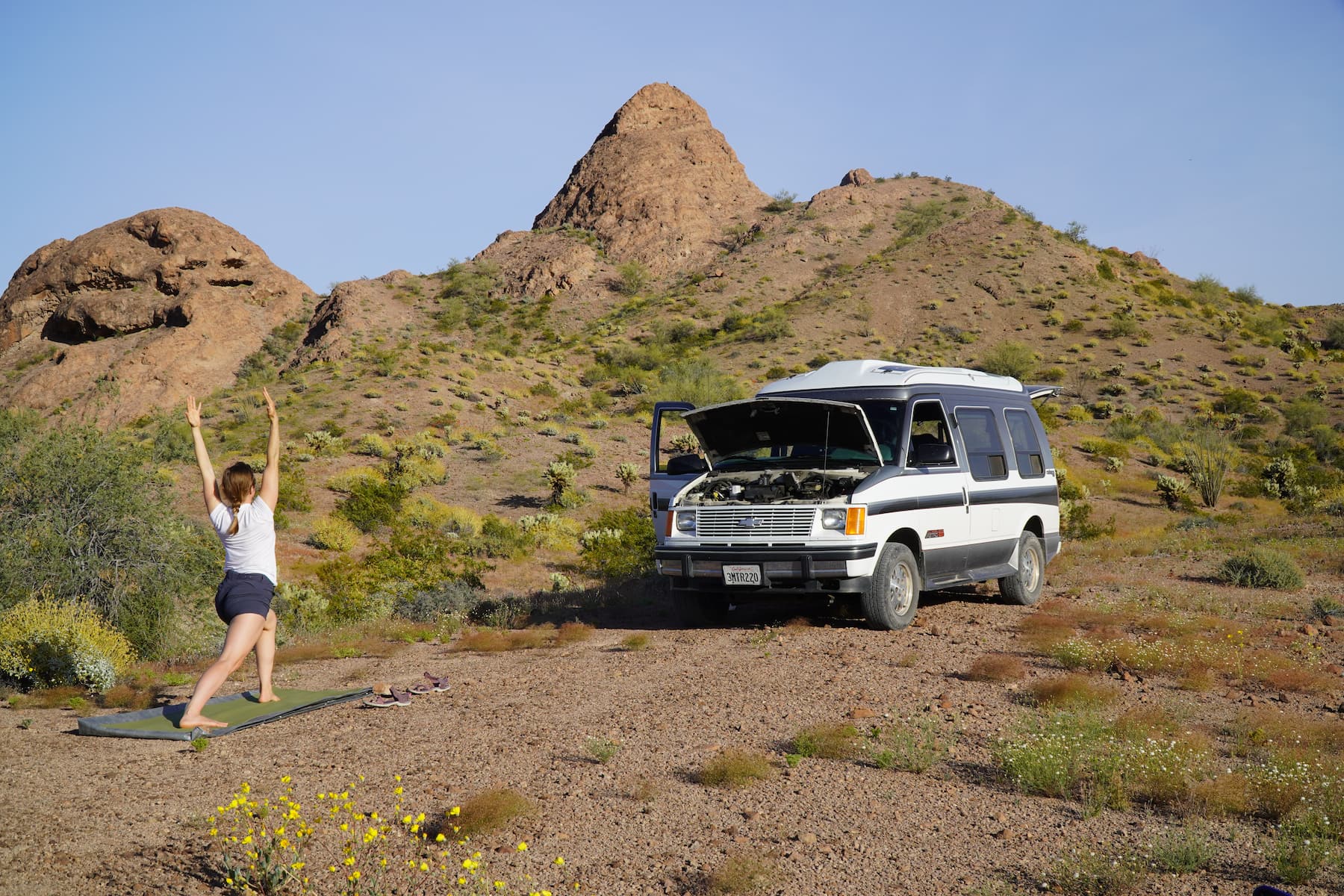 Kristin Hanes founder of The Wayward Home doing yoga in front of her van in the desert.