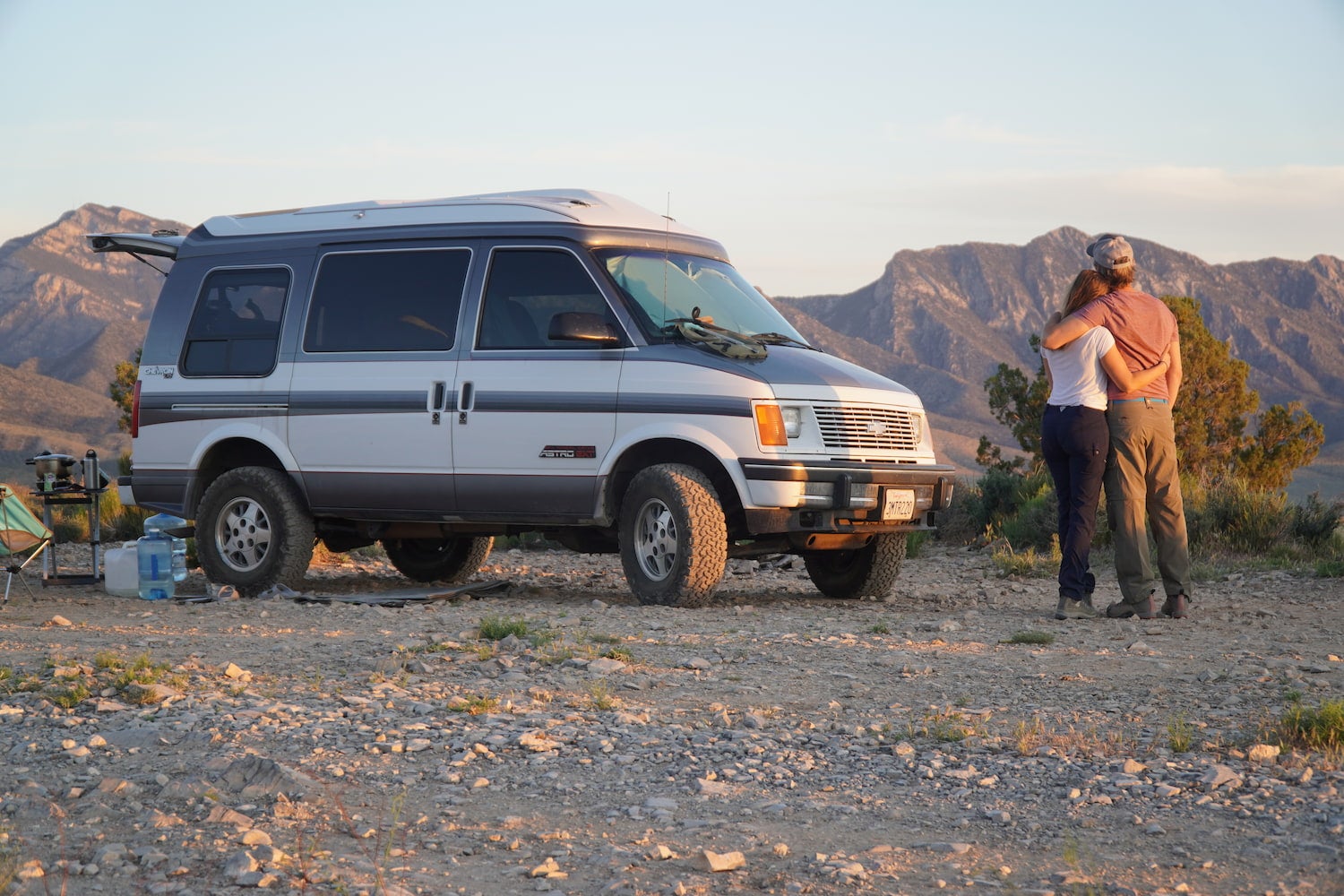 Kristin Hanes of The Wayward home and her prtner embracing beside their van in the desert.