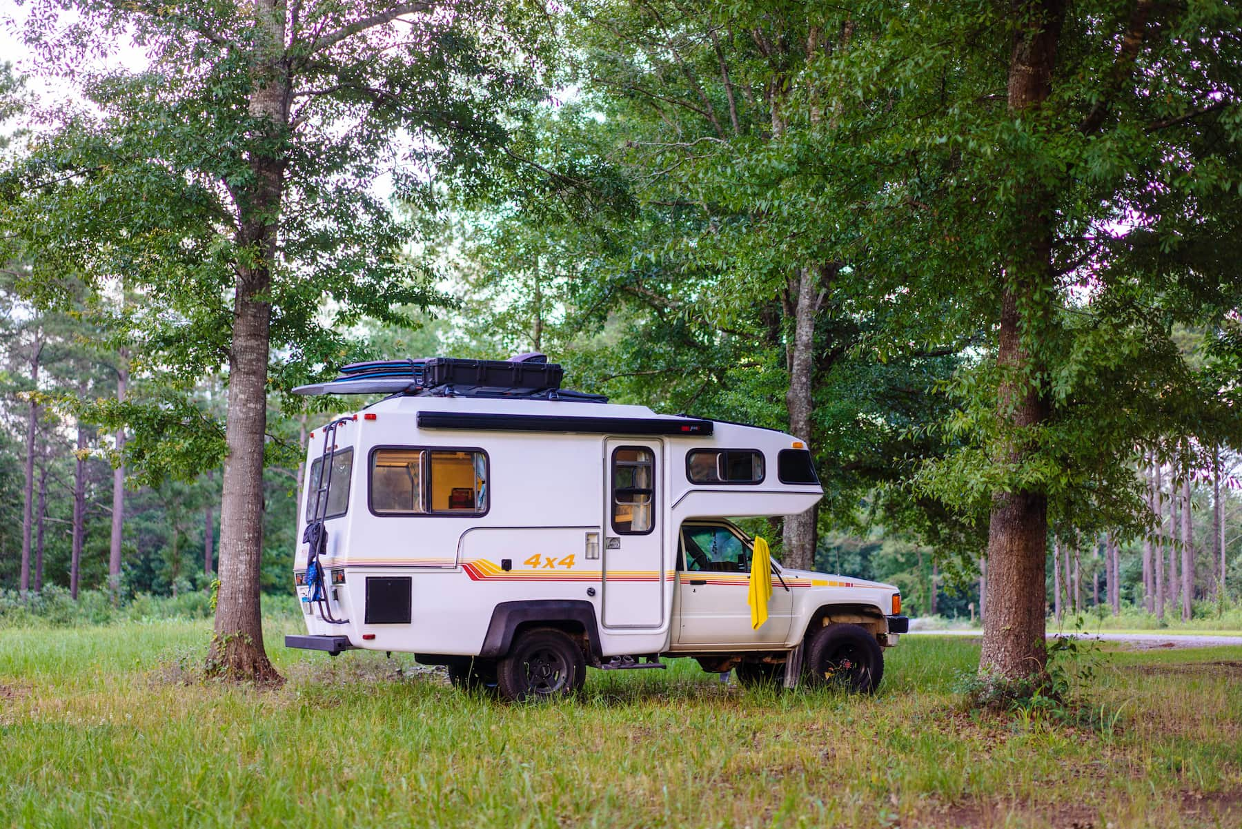 Bound for nowhere's sunraider parked in field and packed with surf boards.