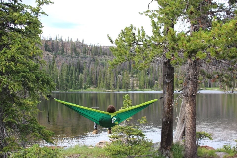 person hammocking by mountain lake