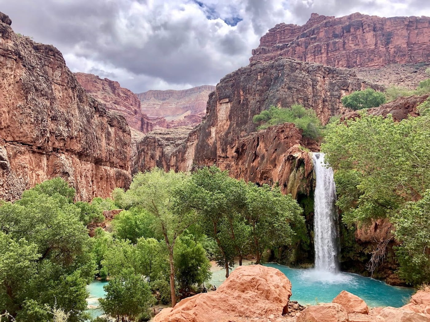 Turquoise waterfall cascading over the red rocks of the iconic Havasu Falls at the Havasu Falls campground.